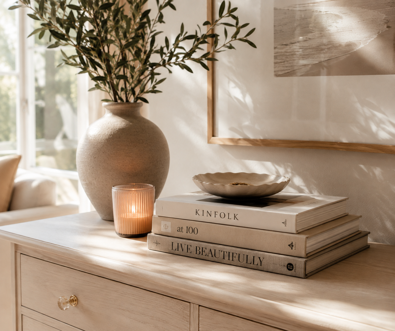 Dresser with stacked books, vase, and candle